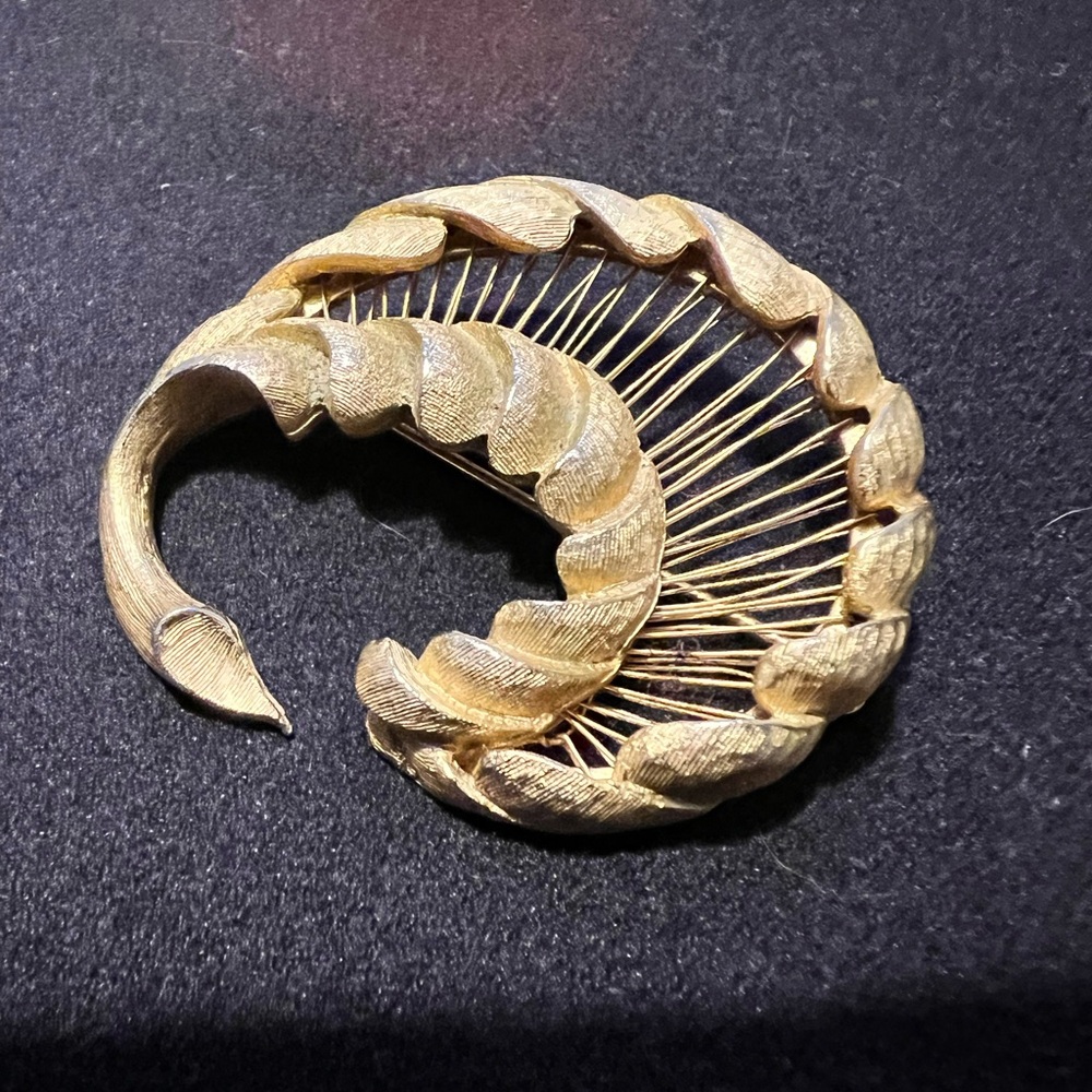 Vintage Monet brushed gold-tone bird like swirl brooch.
